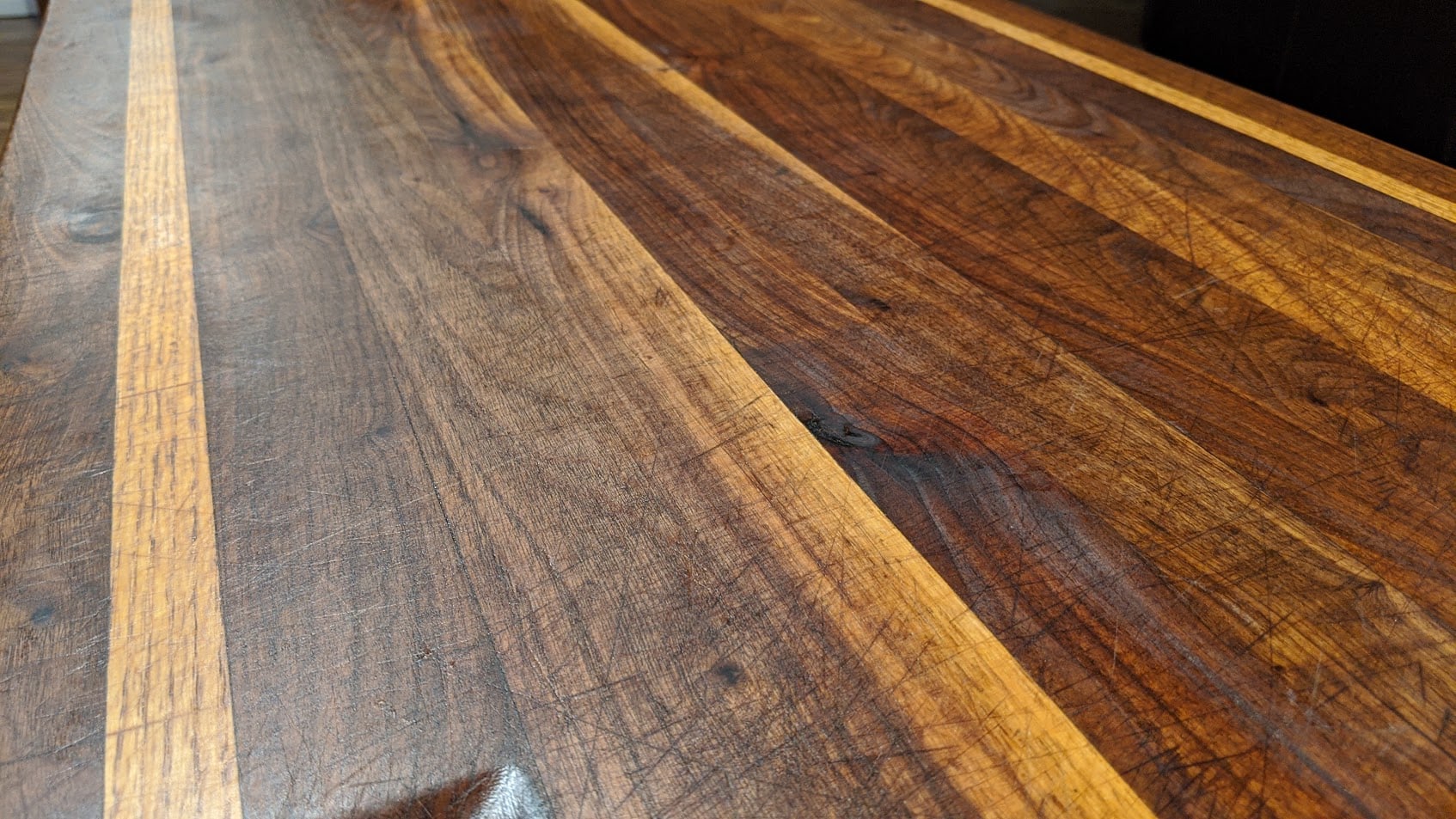A walnut and white oak butcher block top showing cut marks and deepened color after more than ten years of daily chopping
